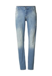 Světlé modré opotřebované džíny s postupným vyblednutím, pěti kapsami a zapínáním na knoflík. Má viditelné roztržení a třepení okrajů.