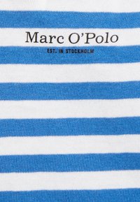 Tessuto a righe blu e bianche con una texture lavorata a maglia. Presenta il logo "Marc O'Polo" e "EST. A STOCCOLMA" in testo nero.