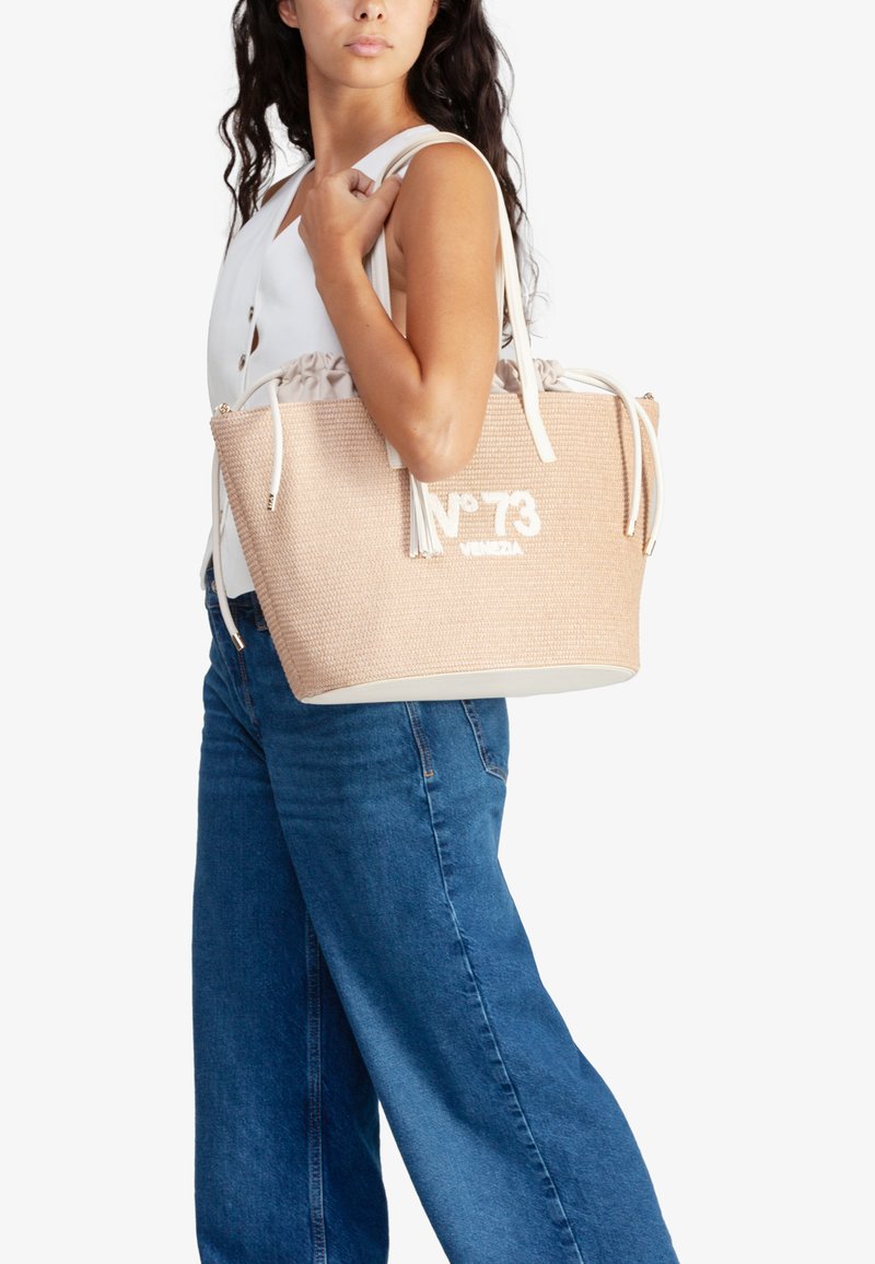 Borsa tote intrecciata beige con branding bianco, chiusura con coulisse e manici chiari. Presenta una forma strutturata e accenti lisci.