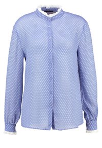 Blouse bleu clair avec un col, boutons sur le devant, manches longues et pois blancs. Présente des volants blancs au niveau du col et des poignets.