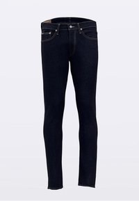 Jean skinny en denim bleu foncé, avec une conception à cinq poches, des coutures dorées et une fermeture par bouton à la taille.