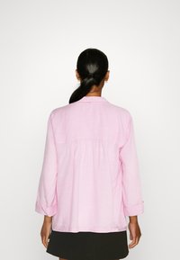 Camicia a maniche lunghe a righe rosa chiaro con piega sul retro e polsini arrotolati. Tessuto morbido e design del colletto classico.