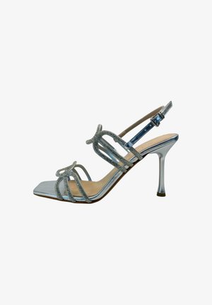 Sandalo argentato metallizzato con tacco alto, punta quadrata, molteplici cinturini decorati con strass e fibbia regolabile alla caviglia.