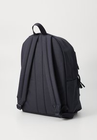 Zwarte stoffen rugzak met gevoerde riemen, handvat aan de bovenkant, zijvak en een gestructureerd ontwerp. Kenmerkt zich door een gladde textuur en minimale hardware.