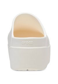 Zuecos Crocs blancos con un acabado suave, parte trasera abierta y un interior texturizado. Presentan un tacón bajo y un sutil logotipo en el lateral.