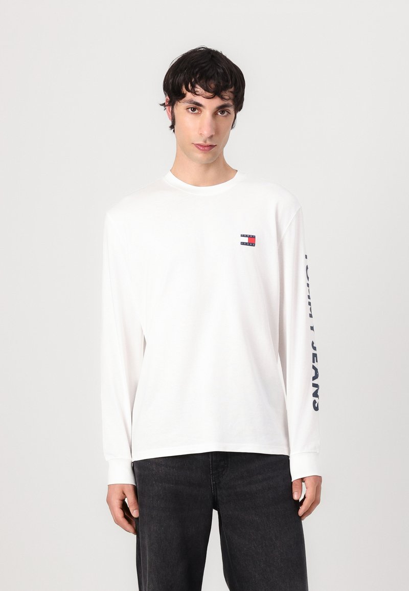 Witte lange mouwen T-shirt van katoen met een ronde hals, met een klein logo op de borst en "TOMMY JEANS" in marineblauw gedrukt op de mouw.