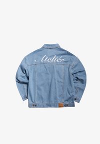 Veste en jean bleu clair vue de dos avec le mot "Ateliér" brodé en blanc sur le haut du dos.