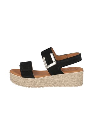 Sandalia cuña de ante negro con gran hebilla plateada, puntera abierta y suela de plataforma beige tejida.