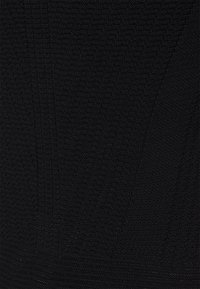 Svart stickad tyg med ett strukturerat mönster, som har vertikala linjer och mjuk ribbning. Materialet verkar elastiskt och slätt.