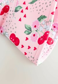 Pink cosmetic pouch made of smooth fabric, featuring a cherry and floral pattern with red hearts and green leaves, structured with stitched edges.