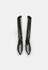 Bottes noires montantes en faux cuir brillant avec une texture crocodile, dotées d'un bout pointu et d'une silhouette ajustée.