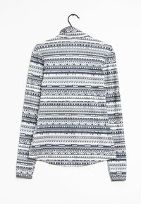 Camisa de manga larga con un patrón geométrico en blanco, azul marino y gris. Presenta un cuello y un dobladillo curvado. Fabricada con un tejido ligero.