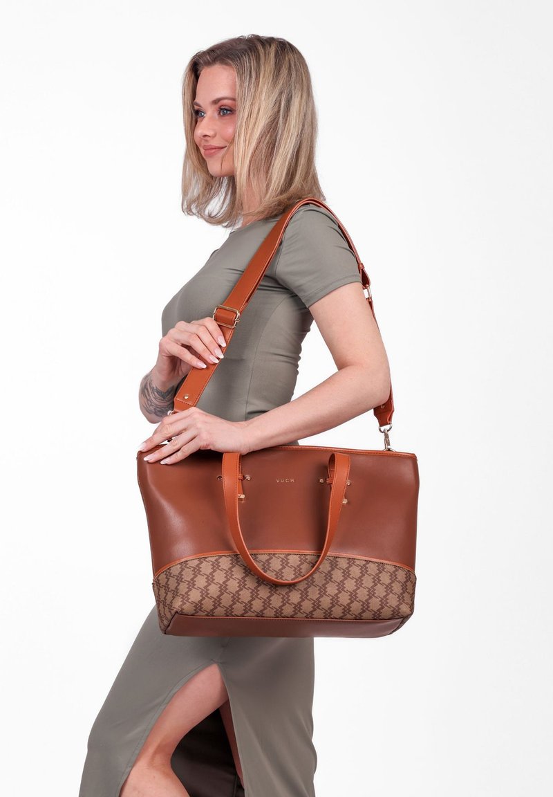 Braune Ledertasche mit einem gemusterten, hellbraunen Grund und langen Griffen. Sie verfügt über einen abnehmbaren Schultergurt und dezente Markenkennzeichnung.