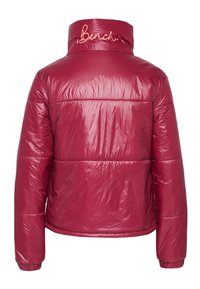 Veste isolante rouge à finition brillante, avec un col montant et le mot "Berch" brodé en rose dans le dos.