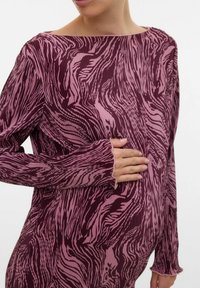Langarm zwangerschapsshirt in roze en diep bordeauxrood met een golvend patroon, met een brede halslijn en ribbelstructuur.