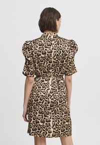 Leopardenmuster-Kleid in Beige und Schwarz, mit Puffärmeln, taillierter Taille und einem glatten, fließenden Stoff. Mittellange bis zu den Oberschenkeln.
