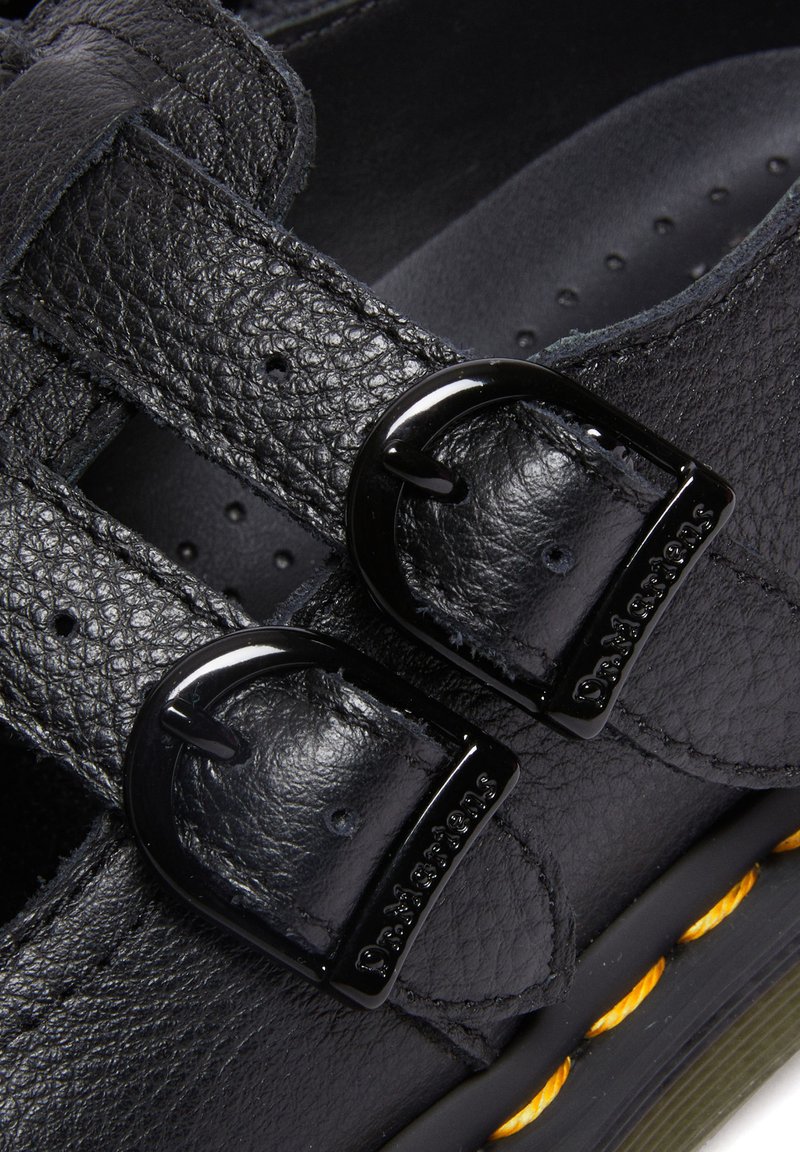 Schwarze Leder-Sandalen mit zwei Schnallenriemen, strukturiertem Obermaterial und gelben Nähten entlang der Sohle. Minimalistisches Design.