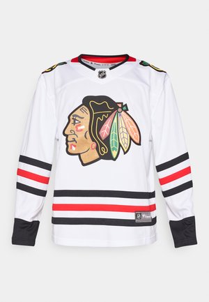 Weißes Eishockey-Trikot mit einem großen Logo im Native American-Stil, roten und schwarzen Streifen an den Ärmeln und am Saum sowie einem runden Halsausschnitt.