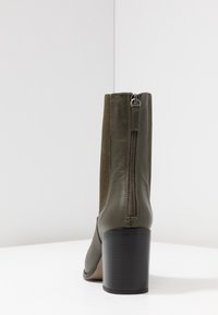 Zielony botek za kostkę z gładkiej skóry, z elastycznymi bokami, z tylnym zamkiem błyskawicznym i masywnym czarnym obcasem.
