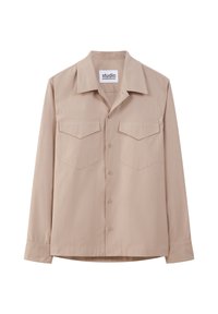 Chemise beige à manches longues en tissu doux, dotée d'un col pointu, d'une fermeture à boutons sur le devant et de deux poches plaquées sur la poitrine.