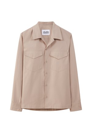 Beżowa koszula z długim rękawem, wykonana z gładkiego materiału, z kołnierzykiem w szpic, zapięciem na guziki z przodu oraz dwoma naszytymi kieszeniami na piersiach.