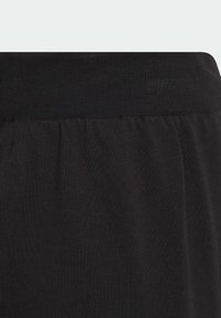 Schwarzer Stoffbund mit weicher Textur und leichter Rippung. Glattes, dehnbares Material setzt sich unterhalb des Bundes fort.