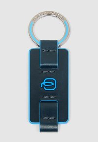 Portachiavi in pelle blu navy con un accento blu, caratterizzato da un anello metallico argento e un logo blu. Texture liscia con dettagli di cucitura visibili.