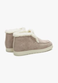 Suède enkelboots in lichtbeige met een fluffy witte kraag, met een gladde textuur en een platte off-white rubberen zool.