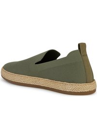 Zapato de lona verde olivo tipo slip-on con parte superior de textil, cortes laterales elásticos y media suela envuelta en yute. Suela de goma para tracción. Diseño ligero.