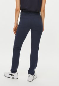 Navyblauwe broek met een slim fit, met twee achterzakken en een soepele, flexibele stof. Draag met witte Nike Air sneakers.