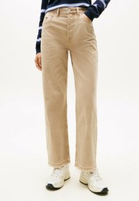 Vaqueros de pierna ancha beige con dobladillo deshilachado, hechos de una mezcla de algodón. Presenta cinco bolsillos y detalles de costura en contraste.