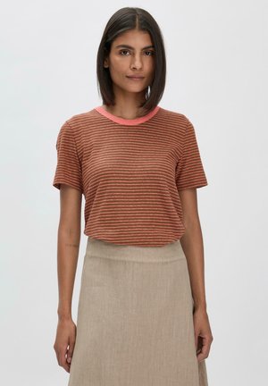 Gestreiftes rostfarbenes T-Shirt mit kurzen Ärmeln und pinkem Ausschnitt, kombiniert mit einem beigen Rock. Glatter Stoff, lockerer Schnitt, simples Design.