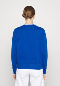 Blauwe crewneck-sweatshirt gemaakt van zachte stof, met een eenvoudig ontwerp, lange mouwen en geribde boorden aan de mouwen en zoom. Effen achterkant.