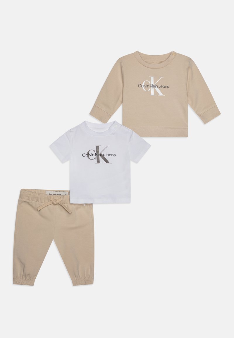 Conjunto para bebé em duas peças, composto por uma tshirt de manga longa bege com logótipo impresso, combinada com uma camisa de manga curta branca e calças jogger bege.