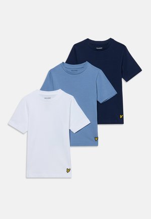 Trois t-shirts unis à manches courtes en blanc, bleu clair et bleu marine, chacun avec un petit logo d'oiseau jaune près de l'ourlet inférieur.