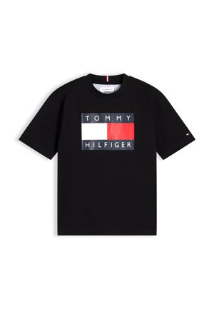 Czarna koszulka z krótkim rękawem, z centralnym logo Tommy Hilfiger przedstawiającym czerwono-białą prostokątną flagę oraz nazwę marki powyżej i poniżej.