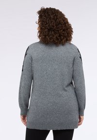 Pulover tricotat gri cu o croială lungă, decolteu rotund și mâneci lungi. Prezintă accente negre texturate pe umeri. Material moale și neted.