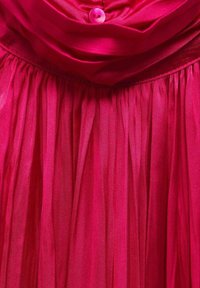 Vestito fucsia con busto arricciato e gonna plissettata fluente. Presenta un collo rotondo e una chiusura con un singolo bottone sulla parte frontale.