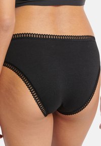 Sort bomulds hipsterunderbukser med bølget blondekant ved taljen og benåbningerne for ekstra detaljer og tekstur.