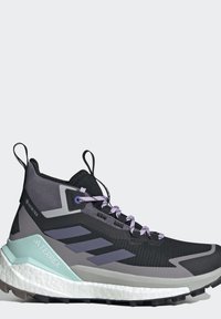 Chaussure de randonnée montante noire et grise avec des lacets violets, une semelle texturée, un tissu Gore-Tex et un maintien de talon bleu clair marqué Terrex.