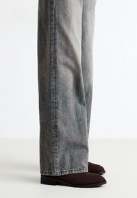 Lysegrå denimbukser med avslappet passform, som har en subtil tekstur og rett ben-design. Kombinert med mørkebrune ankelstøvler.