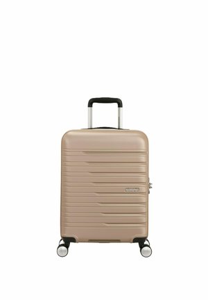 Valigia rigida beige con righe orizzontali, quattro ruote girevoli, manico telescopico e serratura a combinazione laterale.
