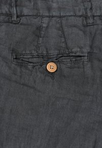 Graue Leinenhose mit einer Vorderasche und braunem Knopfverschluss. Der Stoff hat eine strukturierte Optik und einen sanften Fall.