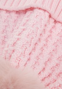 Tessuto rosa lavorato a maglia con motivo strutturato, caratterizzato da un accento morbido e soffice. Il materiale appare spesso e caldo, ideale per il tempo freddo.