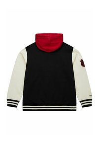 Kapuzenjacke mit schwarzer Rückseite, weißen Ärmeln, roter Kapuze und gestreiften Rippbündchen. Enthält ein Abzeichen am linken Ärmel.