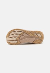 Rubber athletic shoe sole in beige and cream, featuring textured patterns, grooves for traction, and a curved design for flexibility.