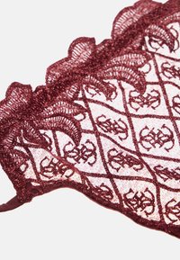 Bralette en dentelle bourgogne avec des motifs floraux complexes, des bords festonnés et une finition texturée, doté de bretelles ajustables.
