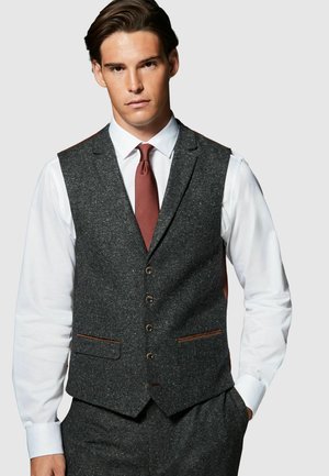 Grau Wolle Vest mit einer strukturierten Oberfläche, fünf Knöpfen, zwei Taschen mit braunen Akzenten, getragen über einem weißen Hemd und einer roten Krawatte.