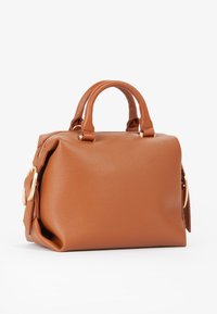 Borsa a tracolla in pelle marrone con doppi manici, dettagli con fibbie color oro e una forma strutturata ma leggermente sformata su uno sfondo bianco.