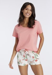 Roze katoenen t-shirt met een ronde hals, gecombineerd met witte shorts met een bloemenpatroon en een trekkoord in de taille.